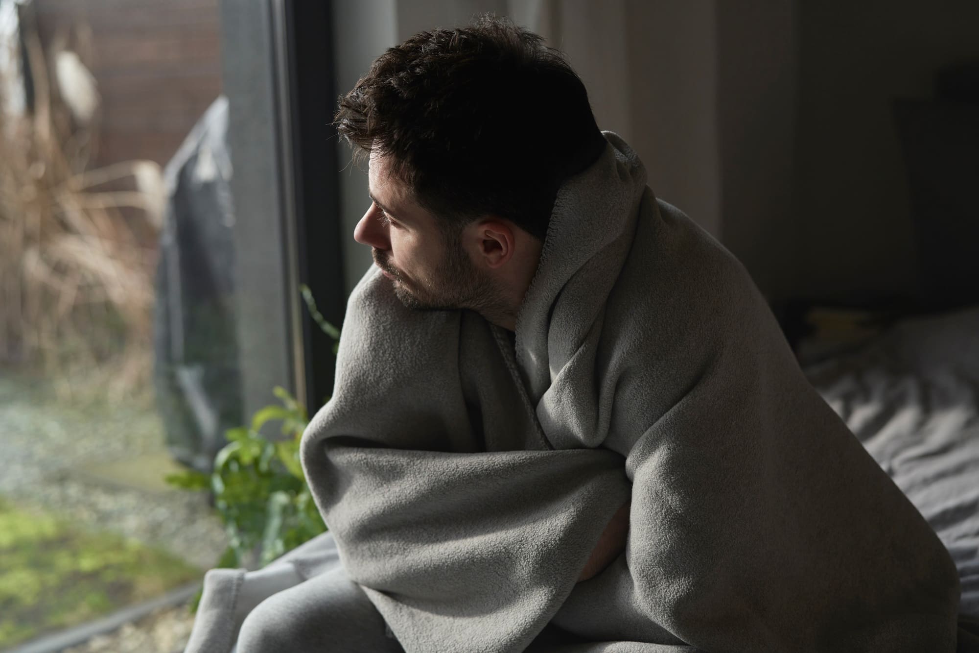 Depressed man covered with a blanket, addicted to fentanyl, seeking treatment