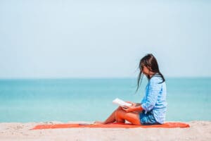 intensive outpatient treatment image with a woman sitting on the beach reading